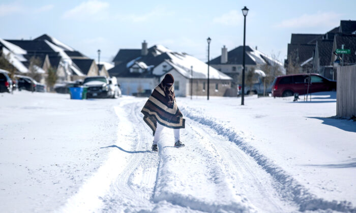 A man walks to his friend's home in a neighbourhood without electricity as snow covers the BlackHawk neighborhood in Pflugerville, Texas, on Feb. 15, 2021. (Bronte Wittpenn/Austin American-Statesman/USA Today Network via Reuters)