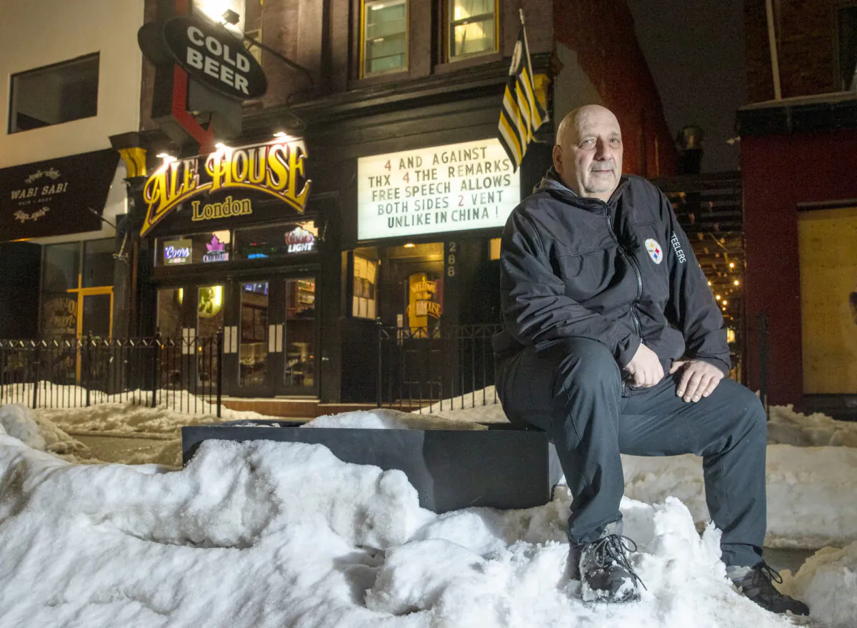 Alex Petro sits outside his bar, Ale House, with his latest sign in the background, in London, Ont., on Feb. 22, 2021. (Jason Ransom)