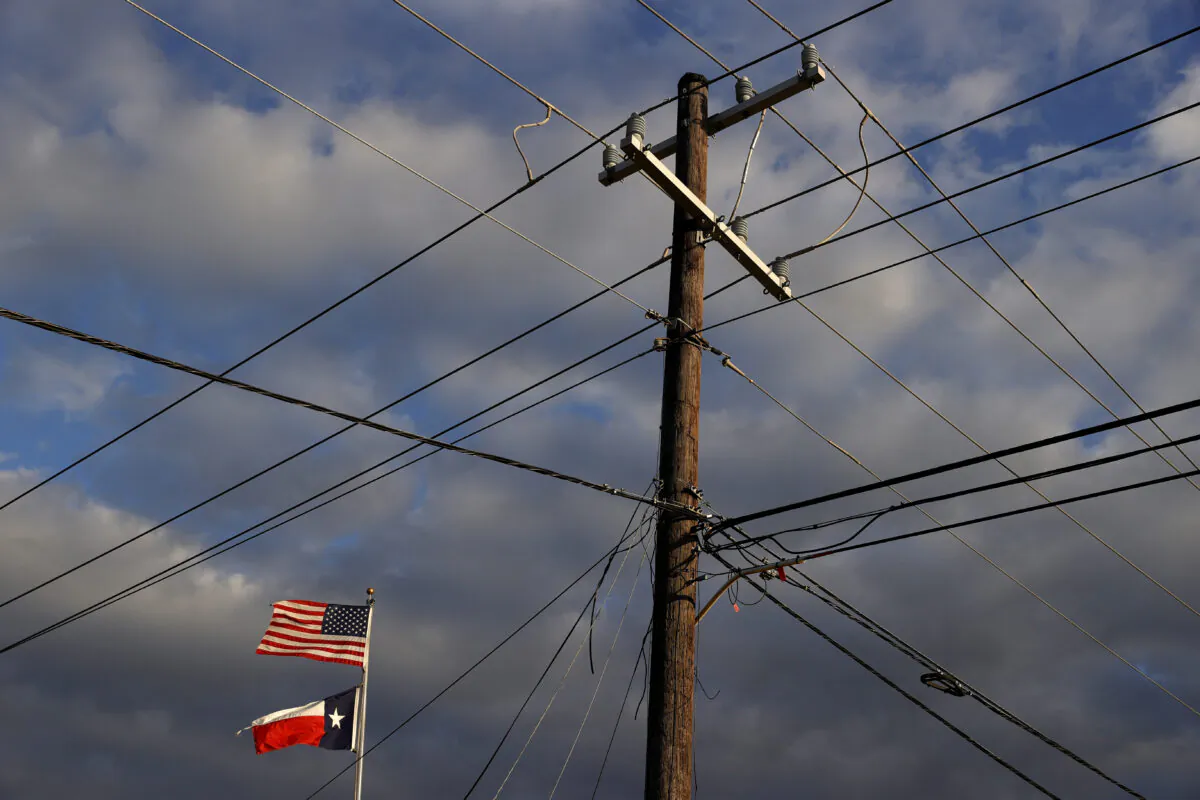 The U.S. and Texas flags fly next to a power pole in Houston, on Feb. 21, 2021. (Justin Sullivan/Getty Images)
