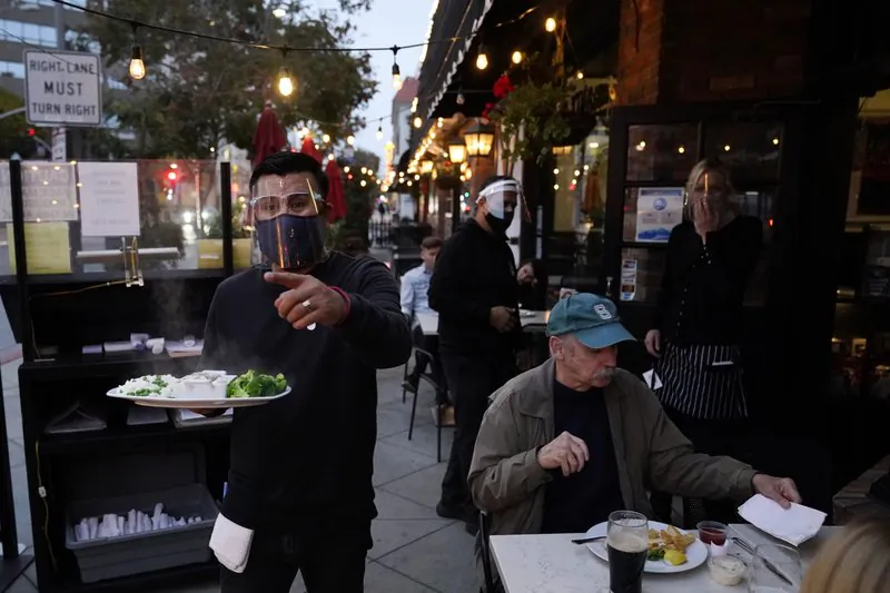 A server carries food for a customer at Ye Olde King's Head in Santa Monica, Calif. on Nov. 19, 2020. (AP Photo/Marcio Jose Sanchez, File)
