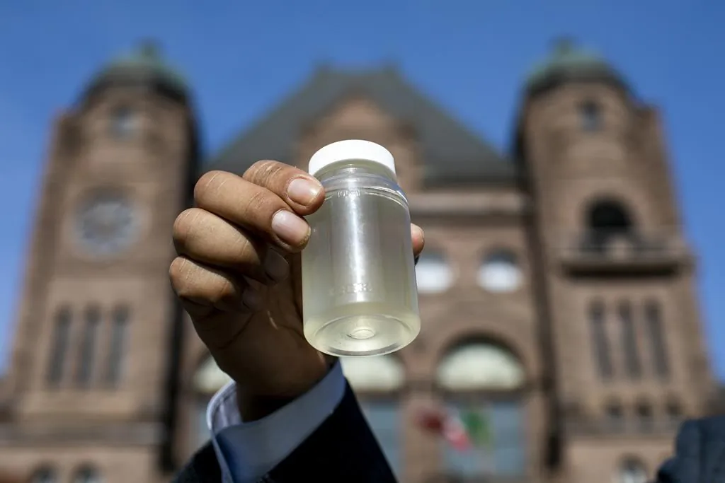 Kiiwetinoong MPP Sol Mamakwa holds up water collected from Neskantaga First Nation, where residents were evacuated over tainted water in October, during a rally at Queen's Park in Toronto on Nov. 6, 2020. (Carlos Osorio/The Canadian Press)