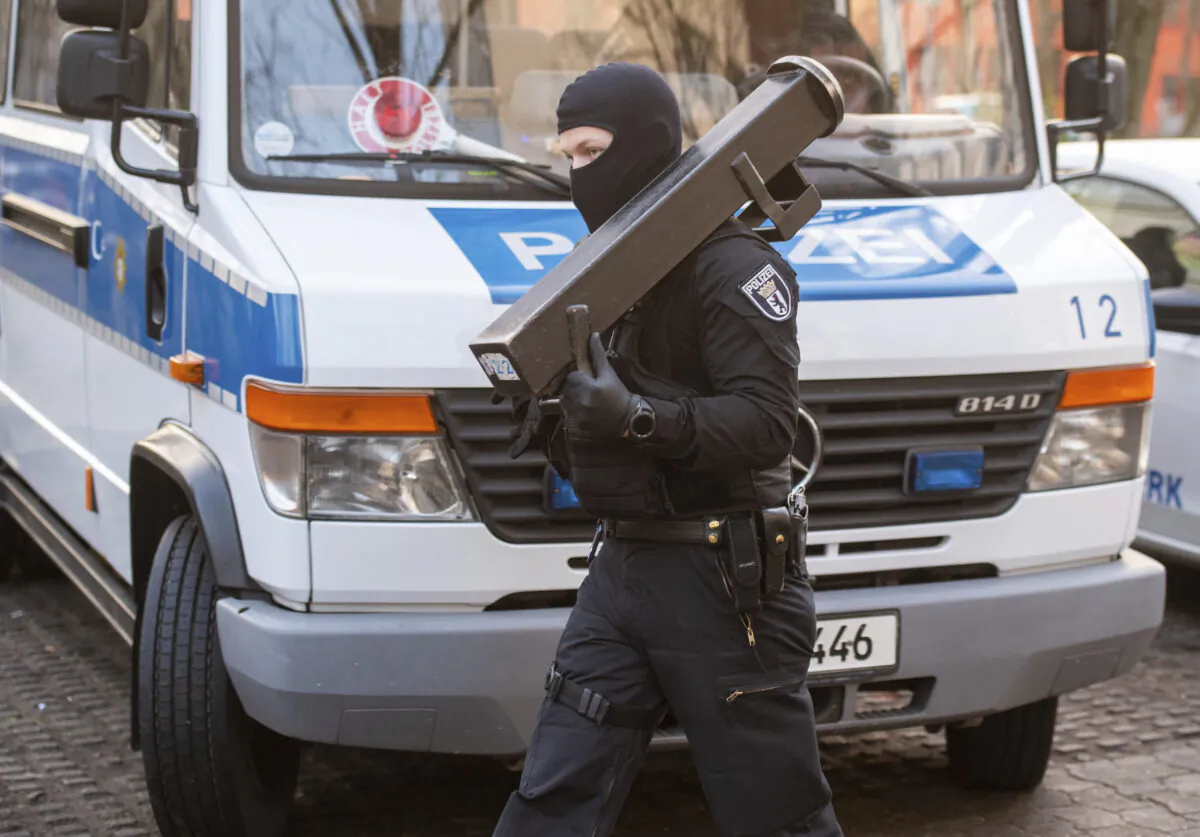 A police walks in front of a car during raids against an Islamist network at the Maerkische Viertel neighborhood in Berlin, on Feb. 25, 2021. (Christophe Gateau/DAP via AP)