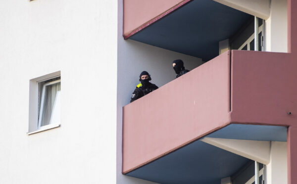 Police officers stand on a balcony of an apartment building during raids against an Islamist network at the Maerkische Viertel neighborhood in Berlin