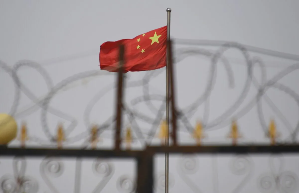 The Chinese flag behind razor wire at a housing compound in Yangisar, south of Kashgar, in China's western Xinjiang region, on June 4, 2019. (Greg Baker/AFP via Getty Images)