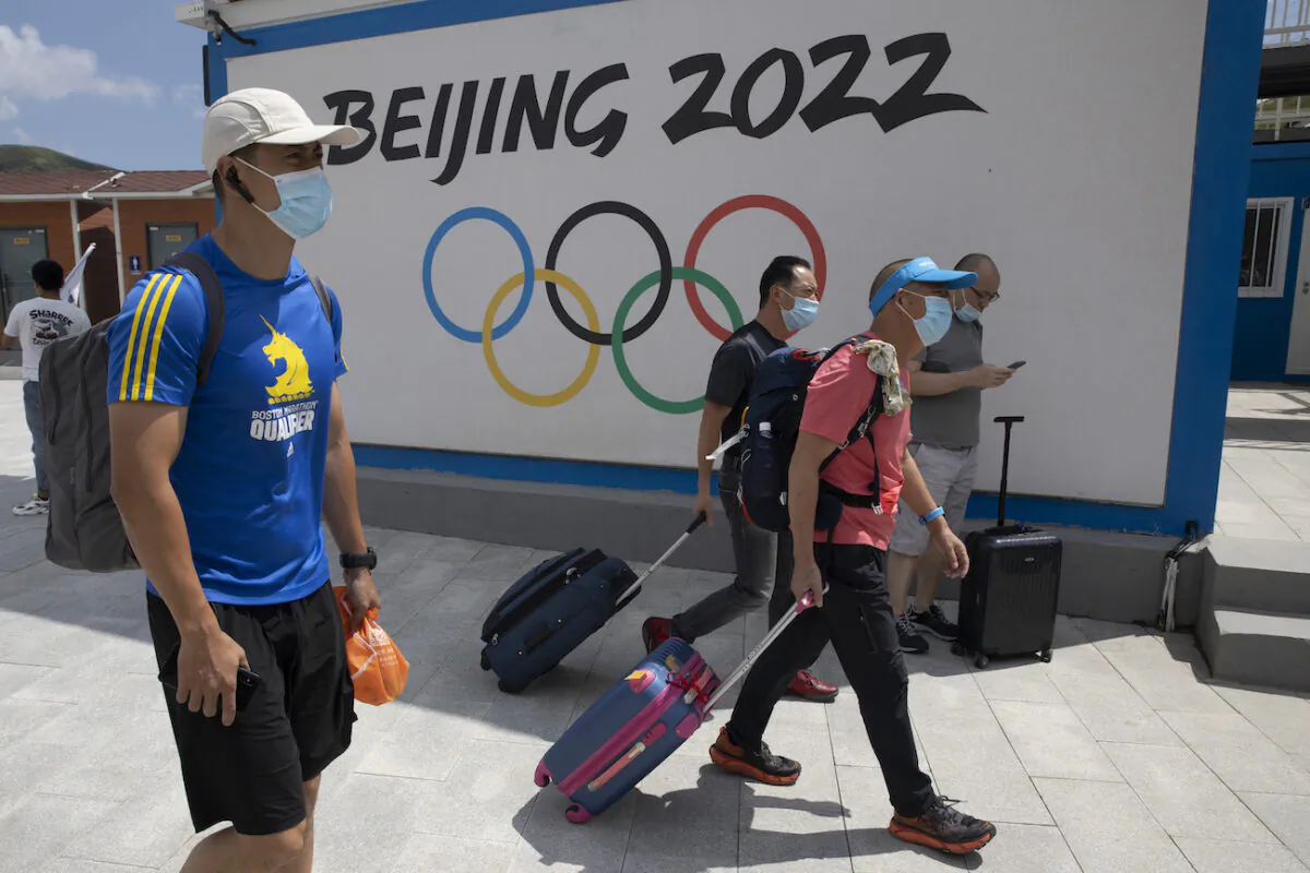 Visitors to Chongli, one of the venues for the Beijing 2022 Winter Olympics, pass by the Olympics logo in Chongli in northern China's Hebei Province on Aug. 13, 2020. (AP Photo/Ng Han Guan)