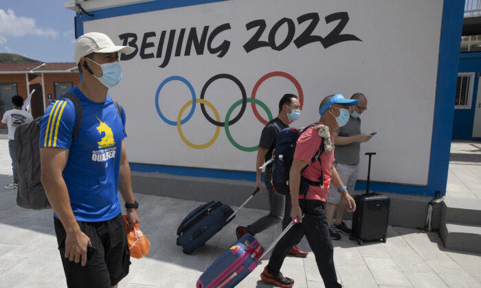 Visitors to Chongli, one of the venues for the Beijing 2022 Winter Olympics, pass by the Olympics logo in Chongli in northern China's Hebei Province on Aug. 13, 2020. (AP Photo/Ng Han Guan)