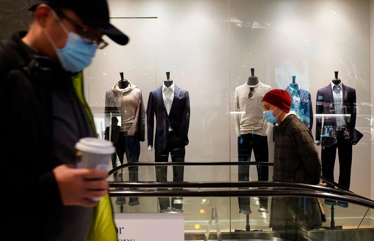 People wearing facemasks pass by a men's clothing store at The Shops at Columbus Circle in New York, on Feb. 15, 2021. (Timothy A. Clary/AFP via Getty Images)