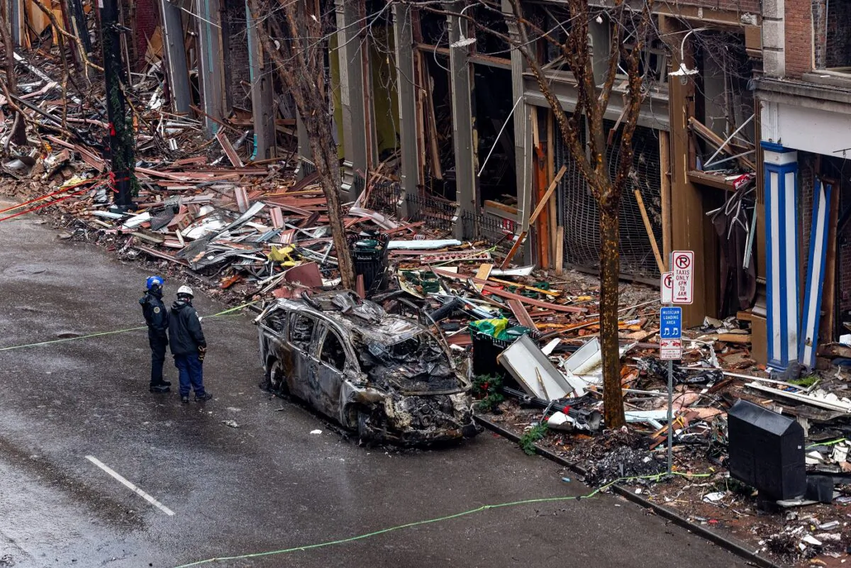 Nashville police officers stand next to an incinerated vehicle and observe damage done to the historic buildings on Second Avenue in Nashville, Tenn. on Dec. 31, 2020. (Alex Kent/Getty Images)