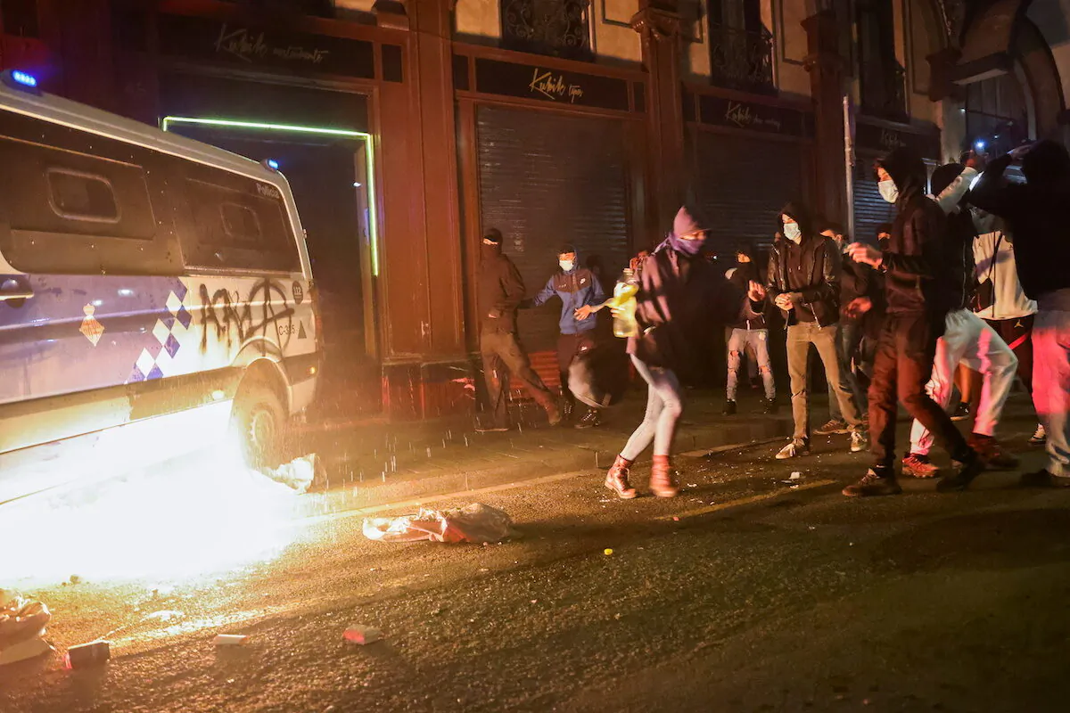 Demonstrators stand next to a burning police vehicle during a protest in support of rap singer Pablo Hasel after he was given a jail sentence on charges of glorifying terrorism and insulting royalty in his songs, in Barcelona, Spain, on Feb. 27, 2021. (Nacho Doce/ Reuters)