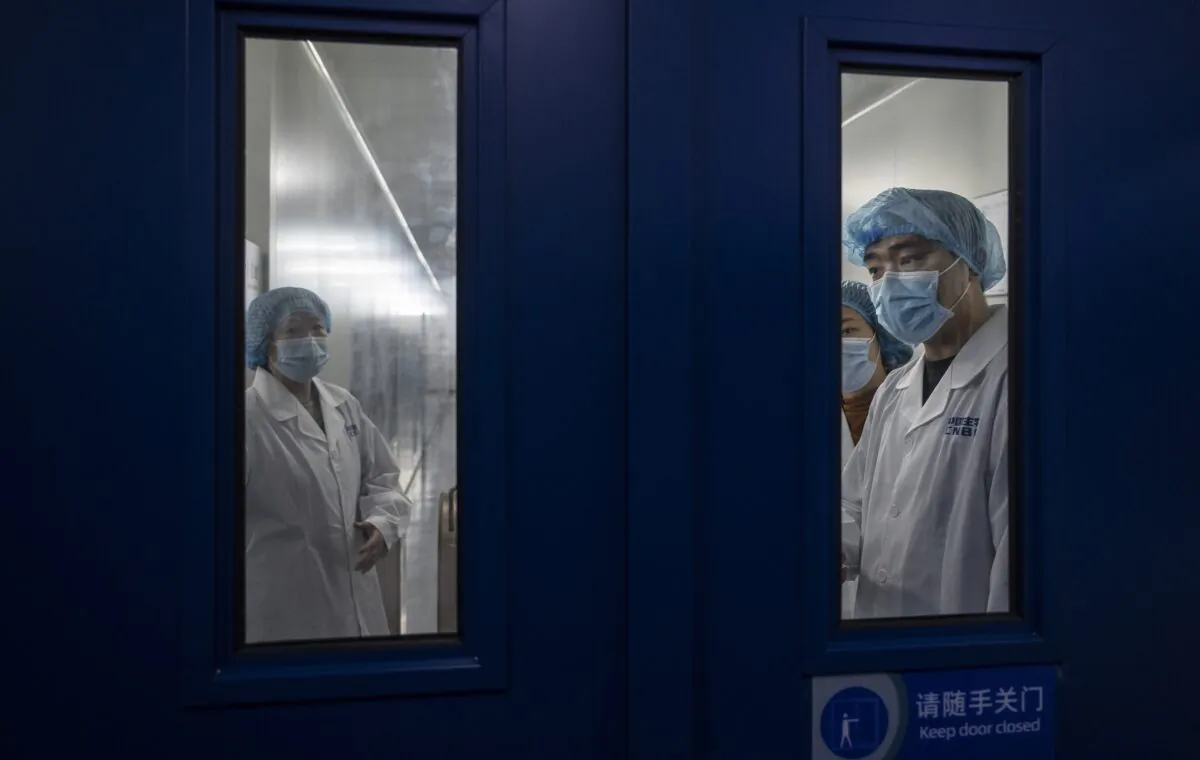 Workers wait to open the secure door in the packaging area of Sinopharm CNBG's inactivated SARS-CoV-2 vaccine for COVID-19 during a media tour organized by the State Council Information Office in Beijing on Feb. 26, 2021. (Kevin Frayer/Getty Images)