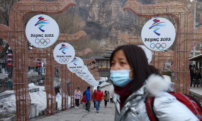 People wear protective masks as they walk front the logos of the 2022 Beijing Winter Olympics at Yanqing Ice Festival on Feb. 26, 2021 in Beijing, China. (Lintao Zhang/Getty Images)