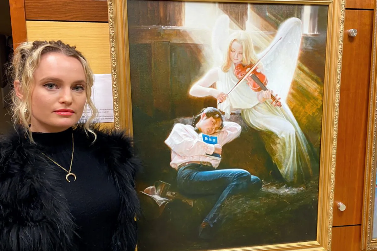 Kelly Pantaleoni stands next to the painting "Homeless II” by Li Yuan at "The Art of Zhen Shan Ren" exhibit in Fullerton, Calif., on Feb. 25, 2021. (Jack Bradley/The Epoch Times)