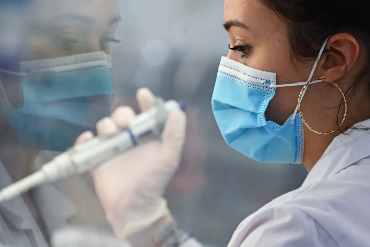 A laboratory technician uses a pipette device to process samples to test for the CCP virus, at Biogroup Laboratory's lab in west London, on Jan. 21, 2021. (Justin Tallis/AFP via Getty Images)