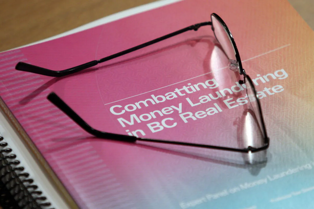 Glasses rest on a copy of Peter German's report into money laundering in the B.C. real estate industry during a press conference at the legislature in Victoria, B.C., on May 9, 2019. (Chad Hipolito/The Canadian Press)