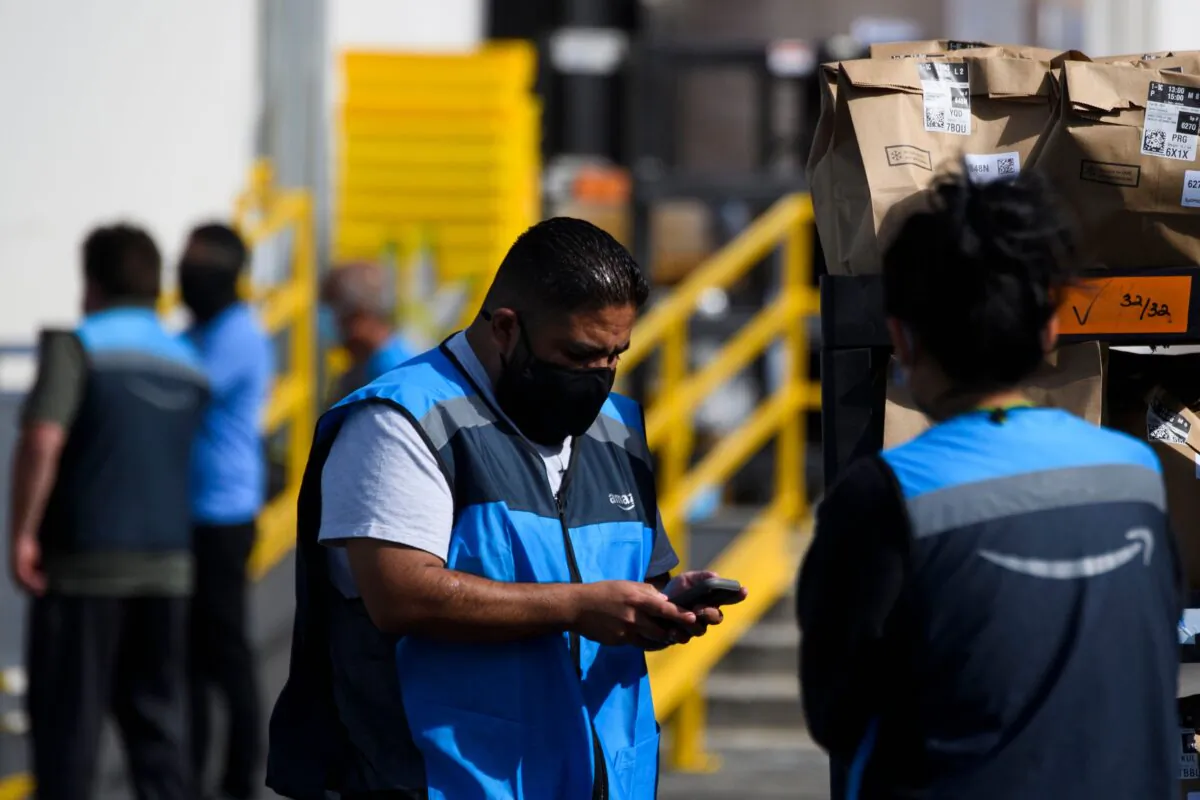 An Amazon delivery driver scans bags of groceries while loading a vehicle outside of a distribution facility in Redondo Beach, Calif., on Feb. 2, 2021. (Patrick T. Fallon/AFP via Getty Images)