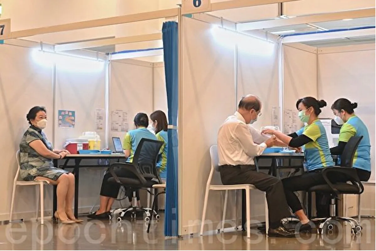 The Hong Kong government has started COVID-19 vaccination for priority groups including people over 60 years old on Feb. 26, 2021. The picture shows two local officials being vaccinated with Chinese-made Sinovac COVID-19 vaccine. (Song Bilong/The Epoch Times)