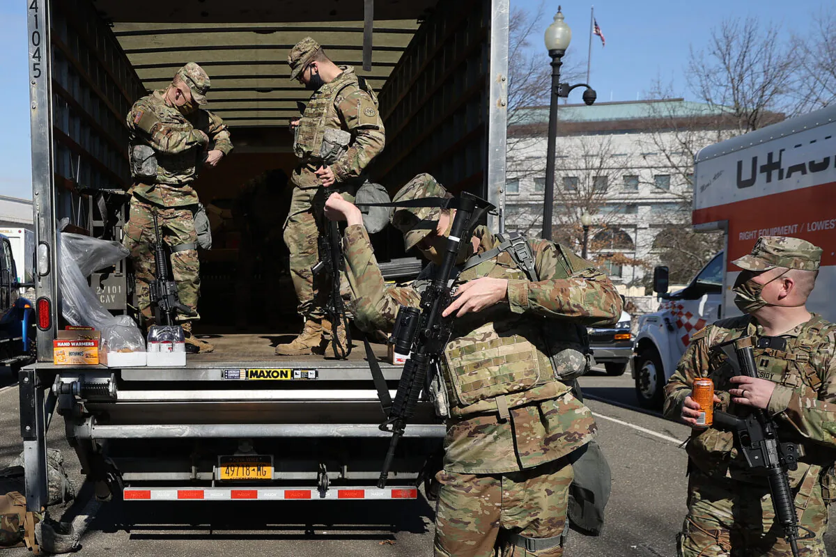 Members of the U.S. National Guard collect long guns from storage vehicles before beginning their shift protecting the U.S. Capitol in Washington on Feb. 8, 2021. (Chip Somodevilla/Getty Images)