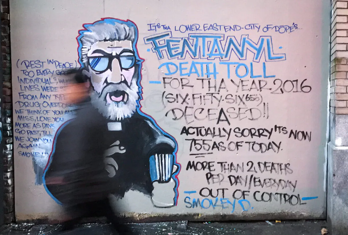 A man walks past a mural by street artist Smokey D. about the fentanyl and opioid overdose crisis in the Downtown Eastside of Vancouver, B.C., Canada, on Dec. 22, 2016. (Darryl Dyck/The Canadian Press)