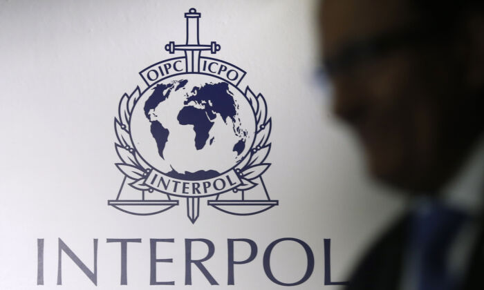 A man passes an Interpol logo during the handing over ceremony of the new premises for Interpol's Global Complex for Innovation, a research and development facility, in Singapore Sept. 30, 2014. (REUTERS/Edgar Su)