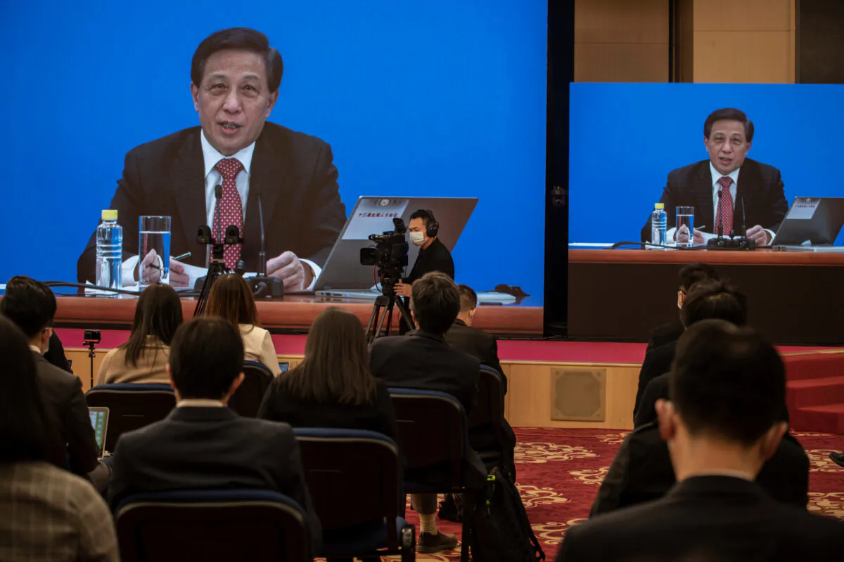 National People's Congress Spokesperson Zhang Yesui is seen on large screens during a video news conference, as a precaution for COVID-19 prevention in Beijing, China, on March 4, 2021. (Kevin Frayer/Getty Images)