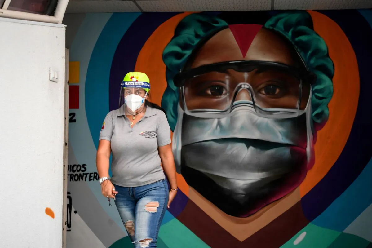 A health worker walks in front of a mural in Caracas, Venezuela, on March 4, 2021. (Yuri Cortez/AFP via Getty Images)