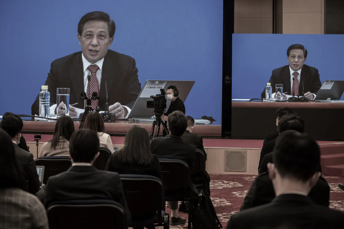 National People's Congress Spokesperson Zhang Yesui is seen on large screens during a video news conference, as a precaution for COVID-19 prevention in Beijing, China, on March 4, 2021. (Kevin Frayer/Getty Images)