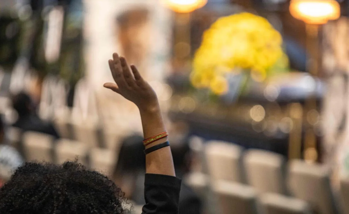 A woman stands and raises her hand as Reverend Al Sharpton gives the eulogy during the memorial service for Andre Hill inside the First Church of God sanctuary in Columbus, Ohio, on Jan. 5, 2021. (Stephen Zenner/AFP via Getty Images)