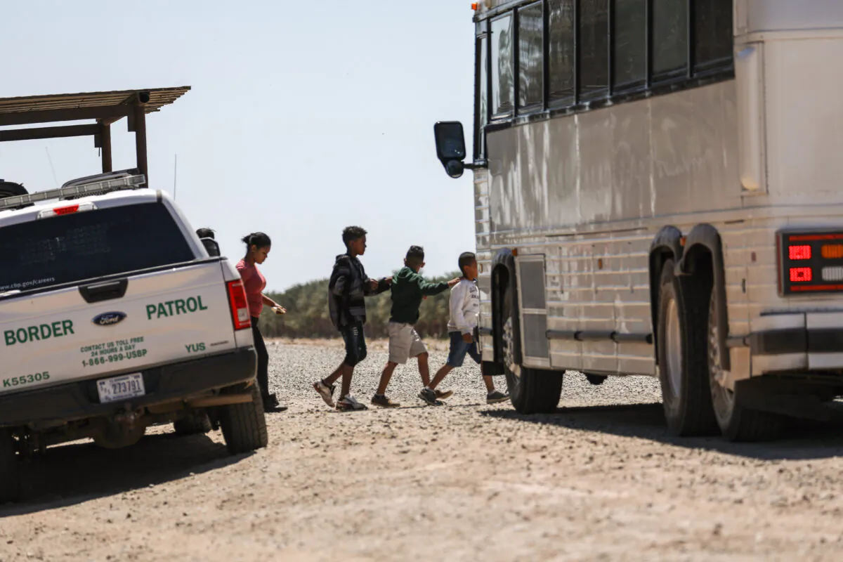 A bus picks up a group of illegal aliens for Border Patrol near the U.S.-Mexico border in Yuma, Ariz., on April 13, 2019. (Charlotte Cuthbertson/The Epoch Times)