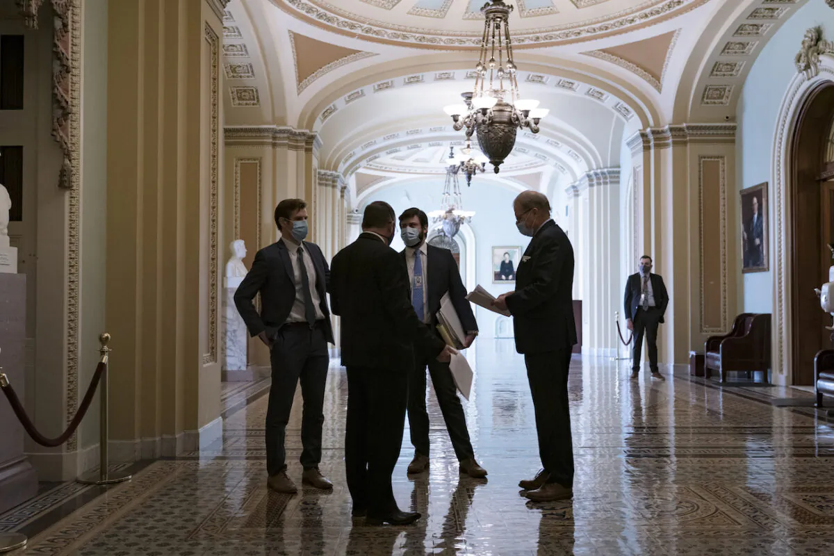 Congressional staffers wait in the ornate corridor outside the Senate chamber during a delay in work on the Democrats' $1.9 trillion COVID-19 relief bill, at the Capitol in Washington on March 5, 2021. (J. Scott Applewhite/AP Photo)