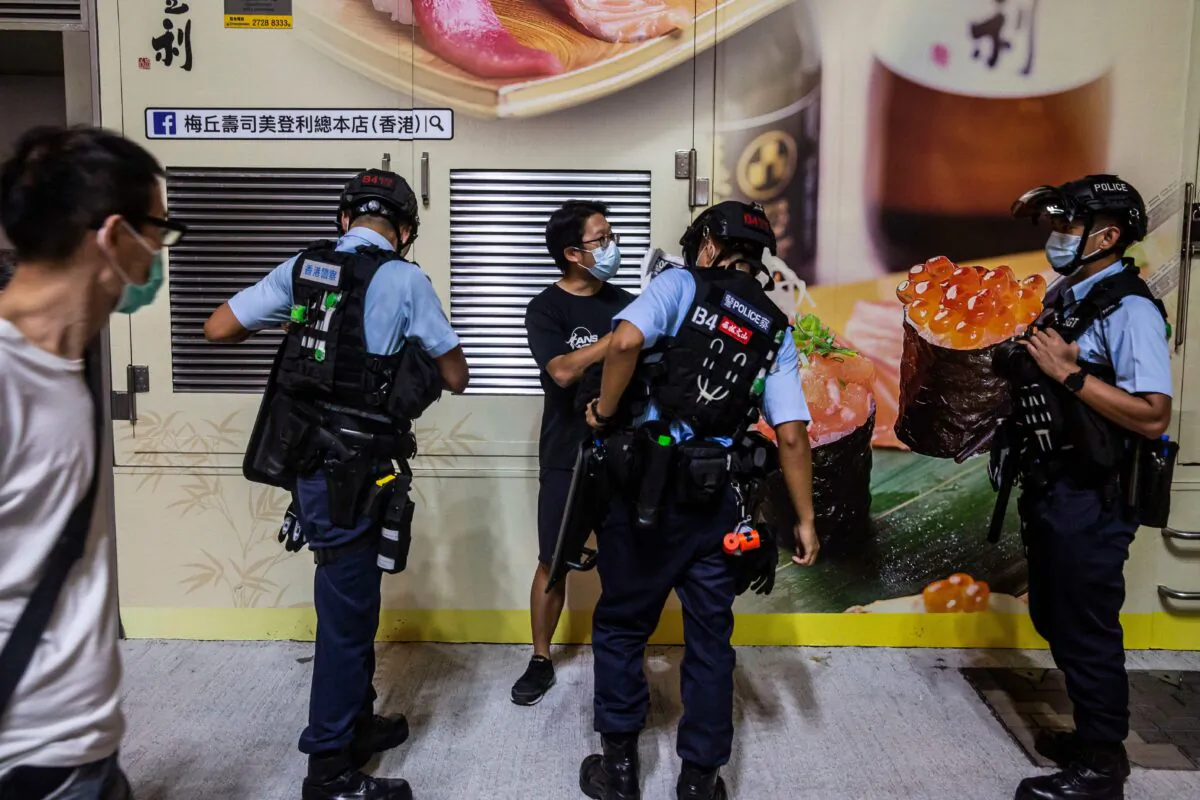 Police conduct an ID check on a man (C) before a planned protest for press freedom in Hong Kong on Aug. 11, 2020, a day after authorities conducted a search of the Apple Daily newspaper's headquarters after the company's founder Jimmy Lai was arrested under the new national security law. (Isaac Lawrence/AFP via Getty Images)