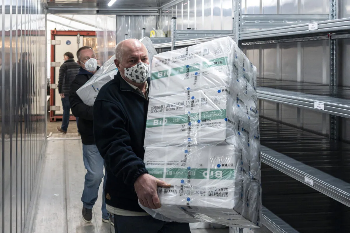 Employees unload the newly arrived coronavirus vaccines from Chinese pharmaceutical company Sinopharm at the logistics base set up to in the parking lot of the government office in the 13th district of Budapest, Hungary, on March 3, 2021. (Zsolt Szigetvary/MTI via AP)