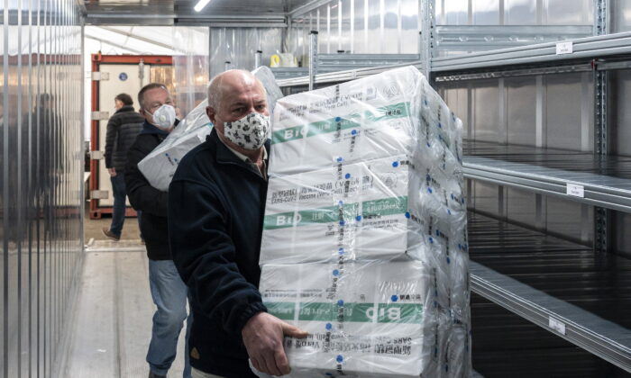 Employees unload the newly arrived coronavirus vaccines from Chinese pharmaceutical company Sinopharm at the logistics base set up to in the parking lot of the government office in the 13th district of Budapest, Hungary, on March 3, 2021. (Zsolt Szigetvary/MTI via AP)