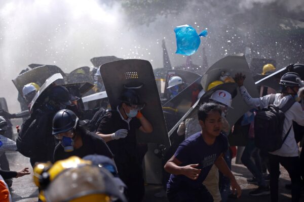 Protesters are dispersed as riot police fire tear gas during a demonstration in Yangon, Myanmar