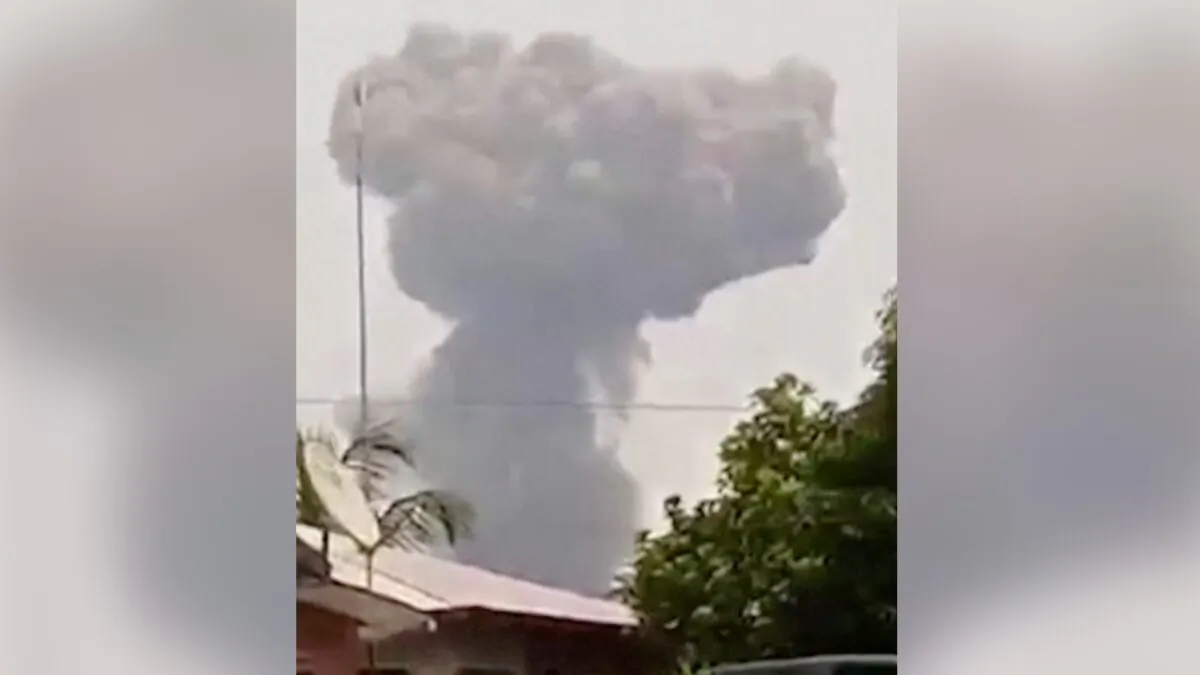 Large cloud of white smoke rising behind a residential building after a series of large explosions at a military base in Bata, Equatorial Guinea, on March 7, 2021. (Screenshot/Courtesy of Modibo Mangoule via Reuters)