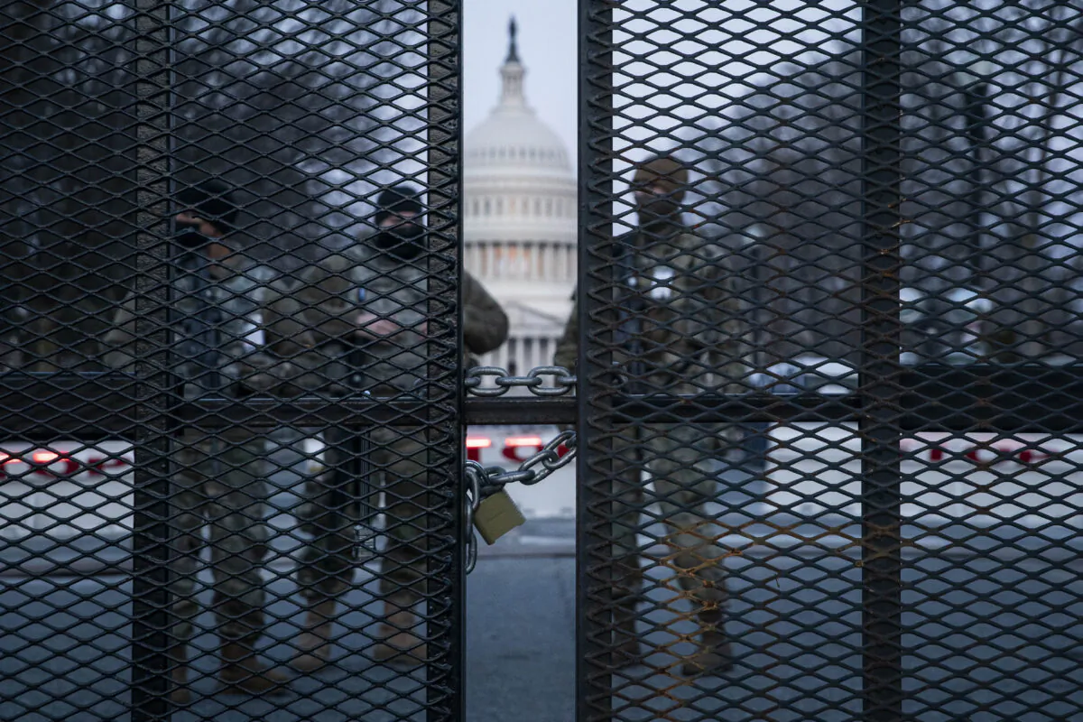 Before sunrise members of the National Guard stand behind a fence perimeter surrounding the Capitol in Washington on March 4, 2021. (Sarah Silbiger/Getty Images)