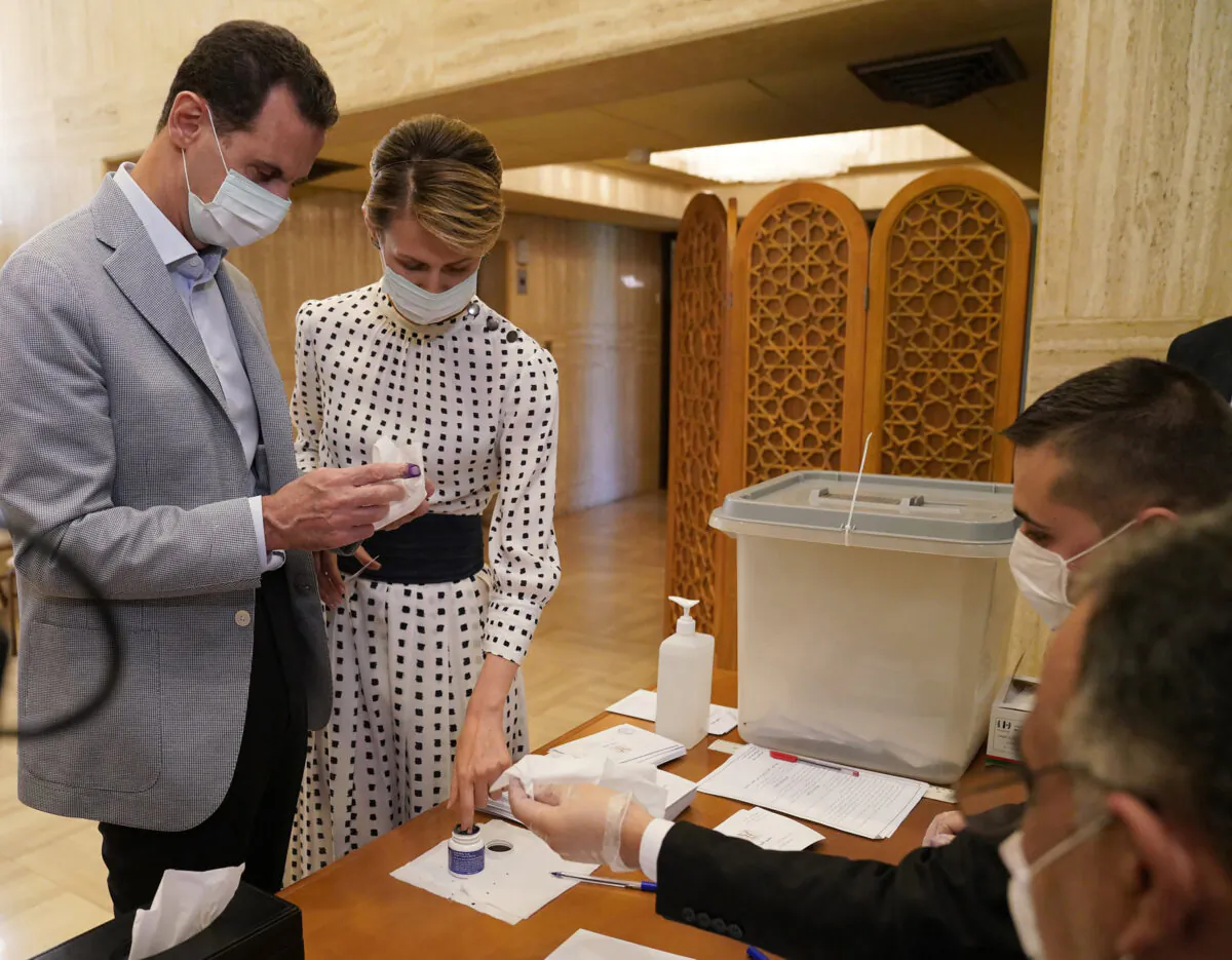 Syrian President Bashar Assad (L) and his wife Asma vote at a polling station in the parliamentary elections, in Damascus, Syria, on July. 19, 2020. (Syrian Presidency via AP)