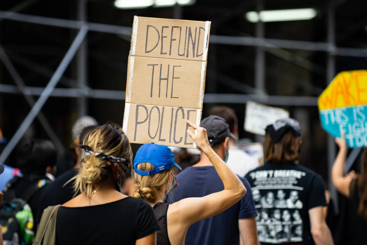 A protester is holding a 'defund the police' sign at a Black Lives Matter protest in Manhattan, New York City on July 13, 2020. (Chung I Ho/The Epoch Times)