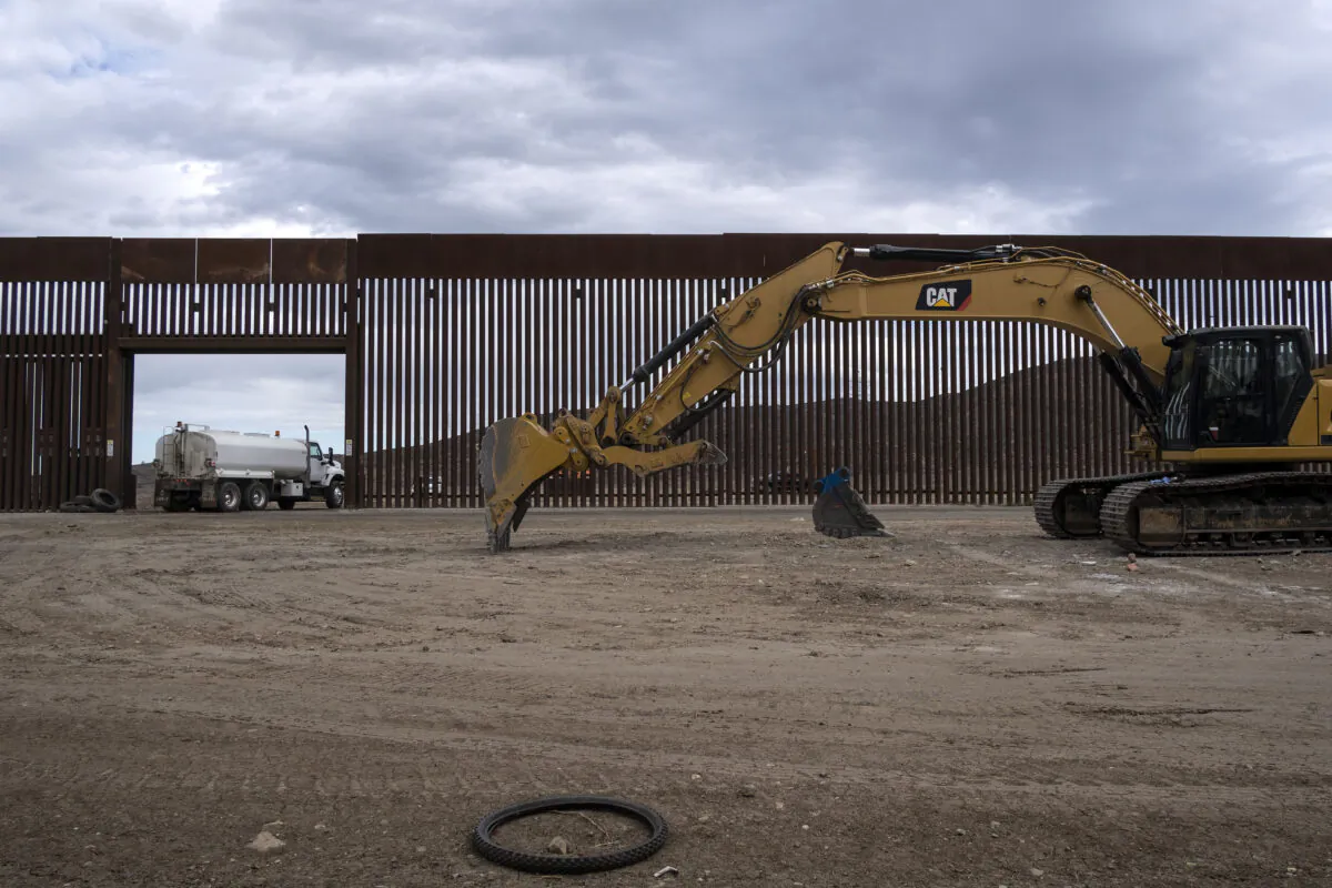 A caterpillar parks between fences at a reinforced section of the U.S.–Mexico border fencing in eastern Tijuana, Baja California state, Mexico, on Jan. 20, 2021. (Guillermo Arias/AFP via Getty Images)