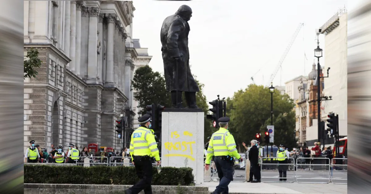 Police officers walk by the defaced statue of Winston Churchill, in London, on Sept. 10, 2020. (Simon Dawson/Reuters)