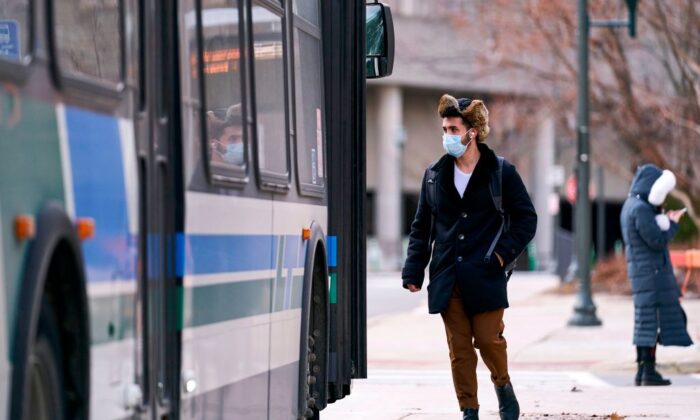 A man in a mask boards a bus on campus at Western University in London, Ontario, Canada, on March 13, 2020. (Geoff Robins/AFP via Getty Images)