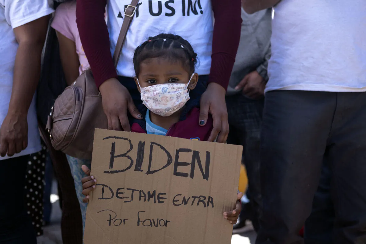 Dareli Matamoros, a girl from Honduras, holds a sign asking President Joe Biden to let her in during a migrant demonstration at San Ysidro crossing port in Tijuana, Baja California state, Mexico on March 2, 2021. (Guillermo Arias/AFP via Getty Images)