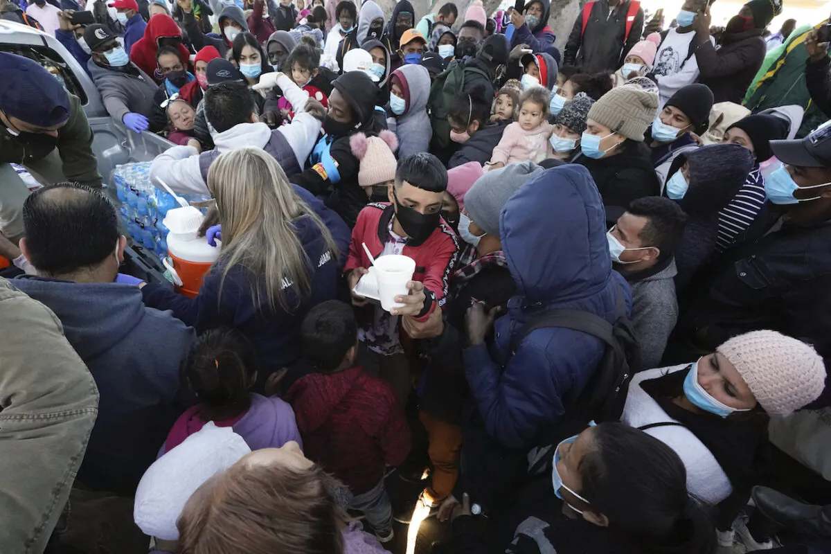 Migrants receive food as they wait for news at the border, in Tijuana, Mexico, on Feb. 19, 2021. (Gregory Bull/AP Photo)