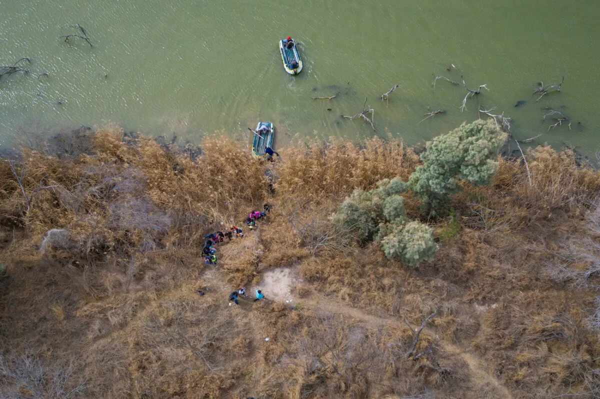 Illegal immigrants climb the banks of the Rio Grande River into the United States as smugglers on rafts prepare to return to Mexico in Penitas, Texas, on March 5, 2021. (Adrees Latif/Reuters)