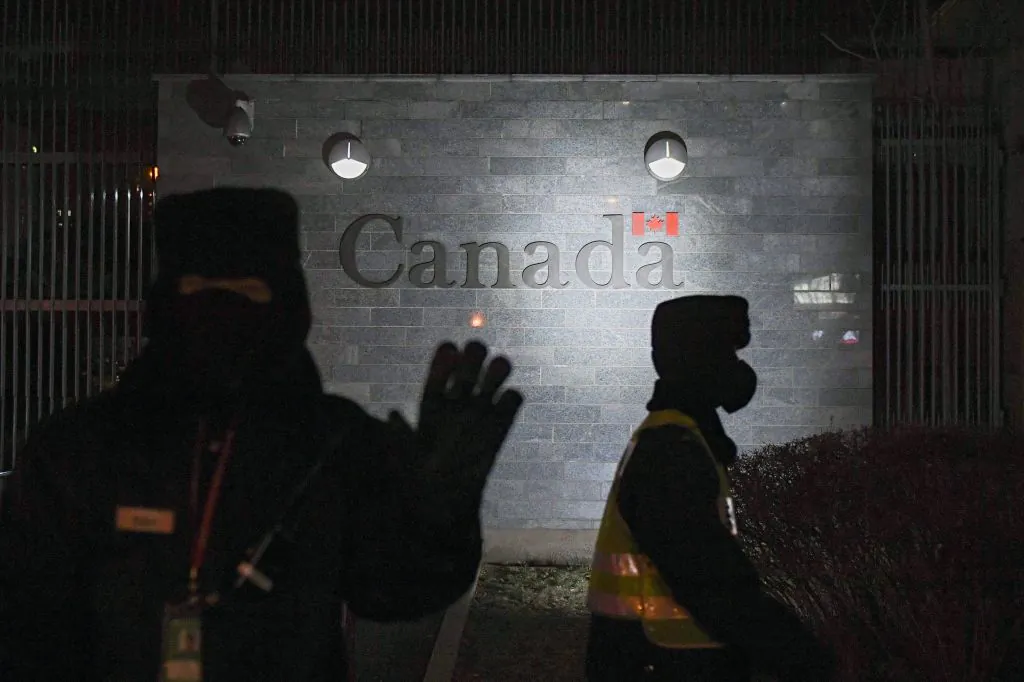 A guard tries to block photos being taken as he and a policeman patrol outside the Canadian Embassy in Beijing on Jan. 14, 2019. (Greg Baker/AFP via Getty Images)