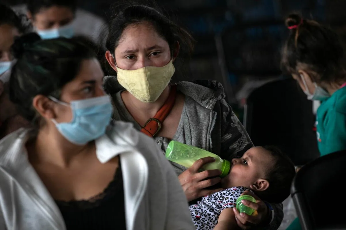 A mother holds her daughter while awaiting COVID-19 test results after being released by U.S. immigration authorities in Brownsville, Texas, on Feb. 25, 2021. (John Moore/Getty Images)