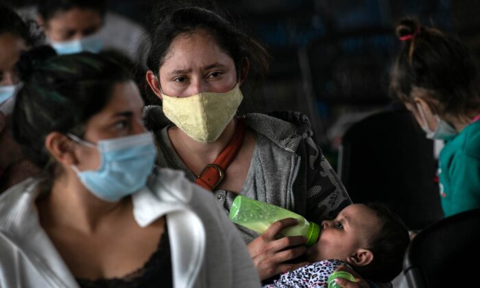 A mother holds her daughter while awaiting COVID-19 test results after being released by U.S. immigration authorities in Brownsville, Texas, on Feb. 25, 2021. (John Moore/Getty Images)