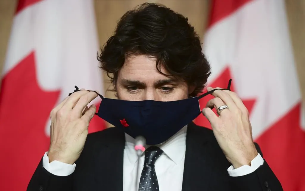 Prime Minister Justin Trudeau puts on his mask at a press conference in Ottawa on Tuesday, Feb. 16, 2021. (THE CANADIAN PRESS/ Patrick Doyle)