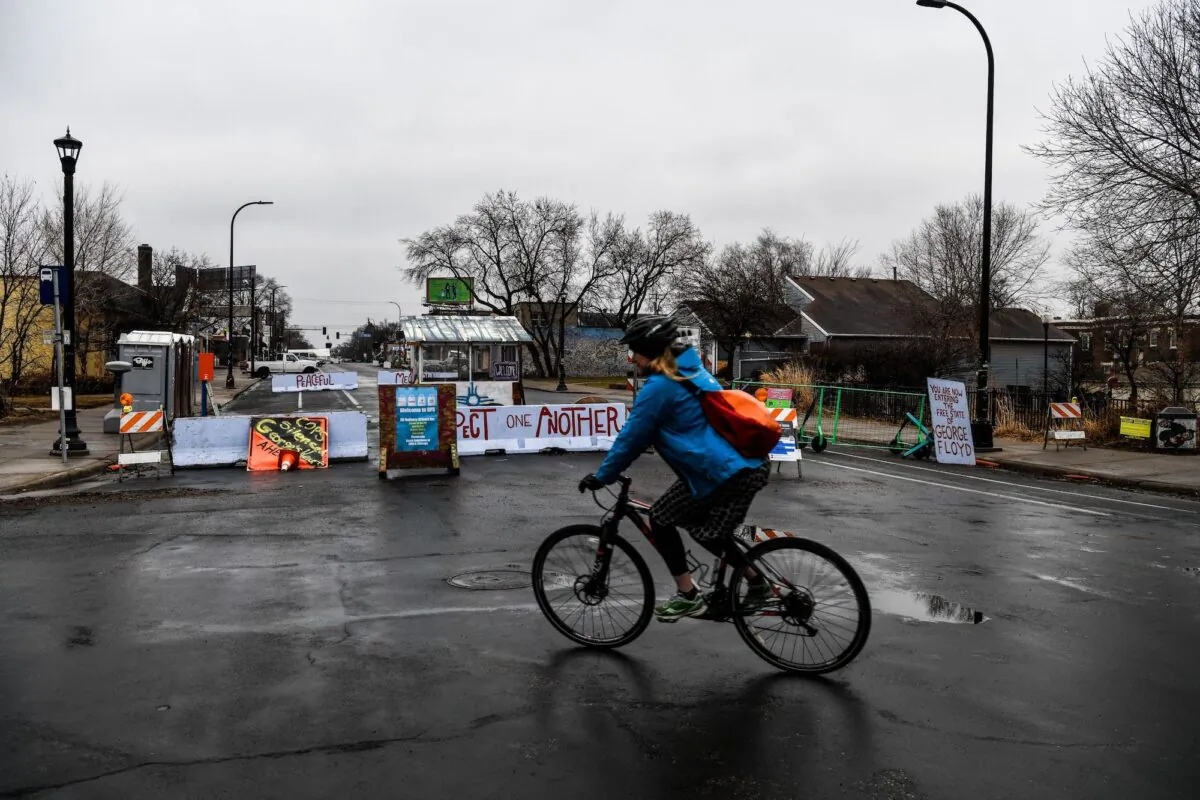 A woman rides past the barricades of the “autonomous zone” near where George Floyd died in May 2020, in Minneapolis, on March 10, 2021. (Chandan Khanna/AFP via Getty Images)