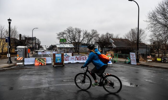 A woman rides past the barricades of the “autonomous zone” near where George Floyd died in May 2020, in Minneapolis, on March 10, 2021. (Chandan Khanna/AFP via Getty Images)