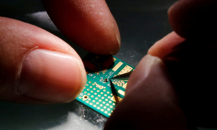 A researcher plants a semiconductor on an interface board during a research work to design and develop a semiconductor product at Tsinghua Unigroup research center in Beijing on Feb. 29, 2016.  (Kim Kyung-Hoon/Reuters)
